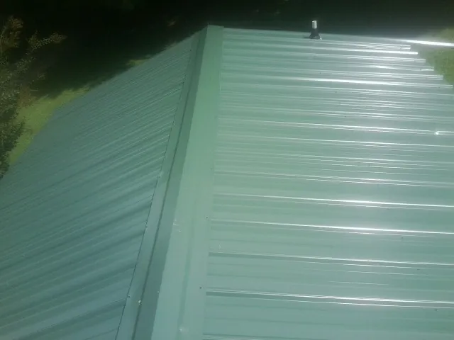 New green metal panels meeting at the ridge of a roof — Flat Roof Repair work by our crew in Long Eddy