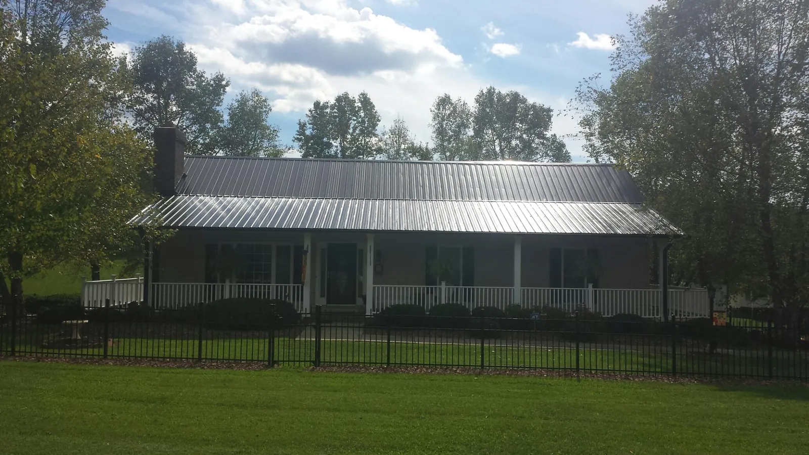 Gray metal roof on a brick ranch with a full width front porch — Gutter Guard Installation work by our crew in Long Eddy