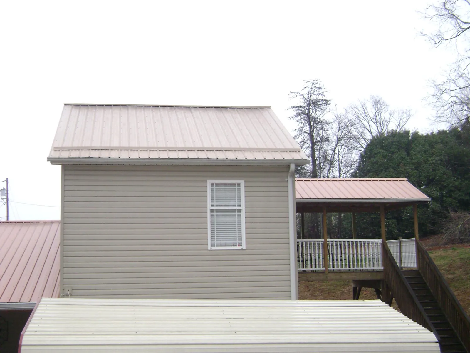 Tan metal roofs on a two story addition and attached porch, from a Roof Replacement job in Long Eddy