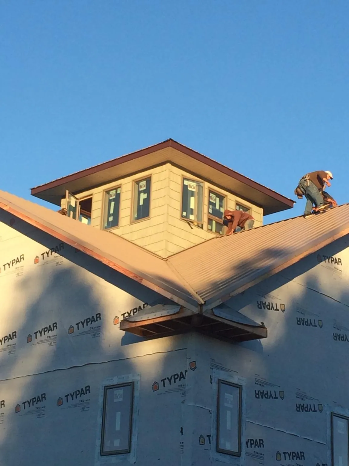 Roofers working around a rooftop cupola on a new metal roof at sunset — Roof Waterproofing in Long Eddy by Roofing Brothers